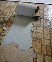 This older style of vinyl flooring has been peeled back to reveal a layer of asbestos beneath, similar to older linoleum that was also manufactured before 1969.