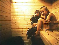 Two smiling children sitting in the sauna.