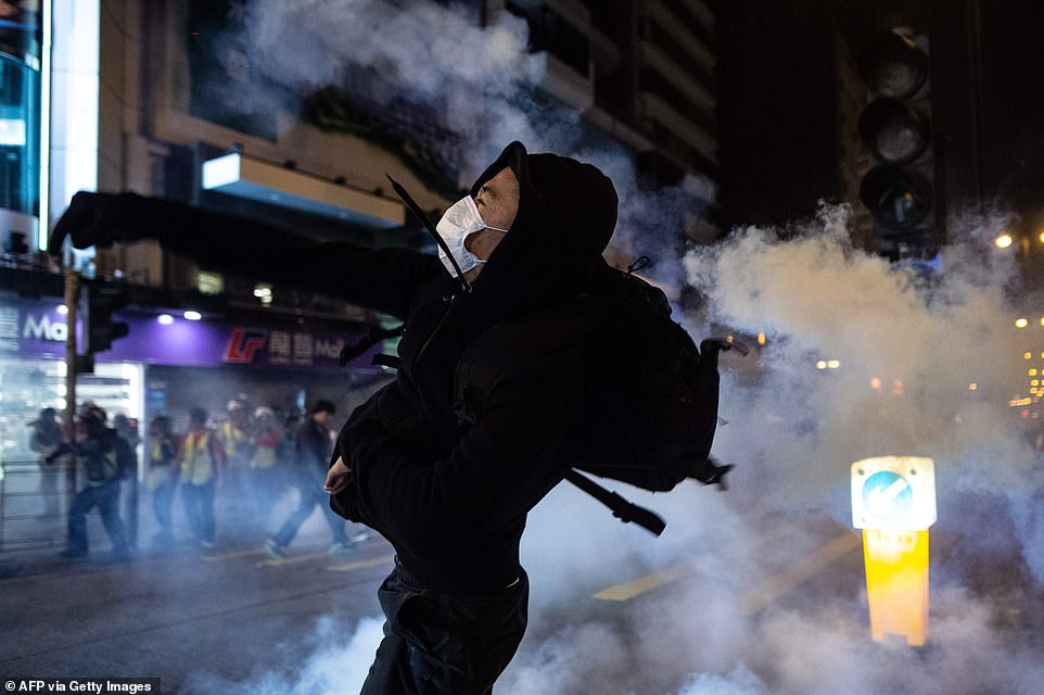 A protester wearing a mask reacts as police in Hong King fire tear gas to disperse bystanders in a protest in the Jordan district of  Hong Kong