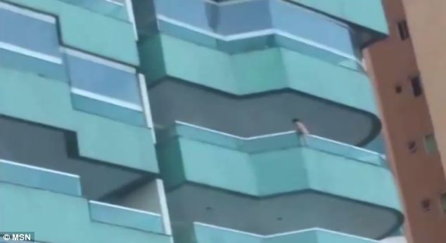 Perilous: The youngster appears to be holding on to the outside of the balcony on a ledge as people screamed down below