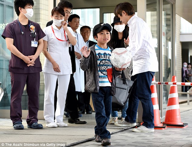 Wearing a baseball cap and a gray jacket over a T-shirt, Yamato waved at the hospital crowd while holding a greeting card in the shape of an oversized baseball