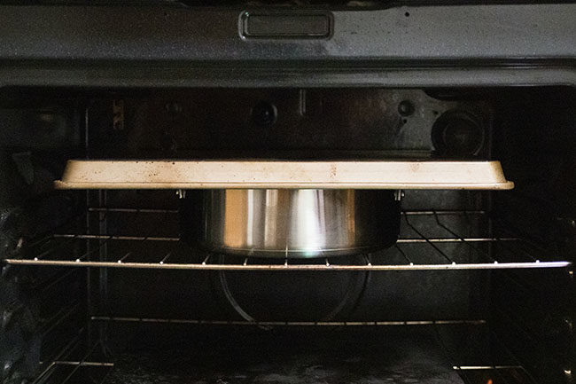 sheet pan on top of stainless steel pot in an oven