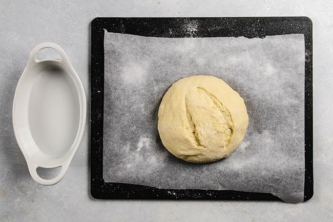 bread dough on a black cutting board lined with parchment paper