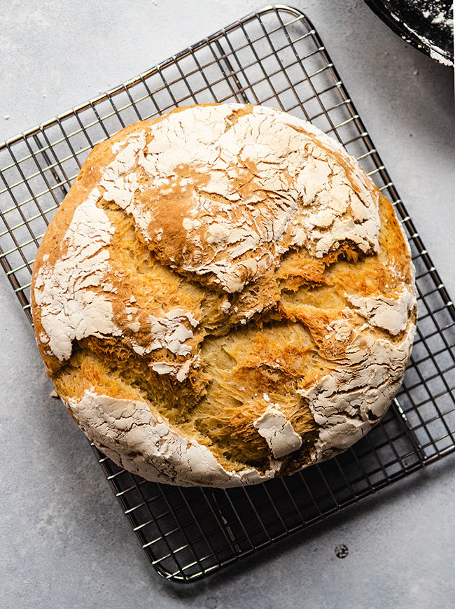 overhead photo of a loaf of crusty bread on a wire cooling rack