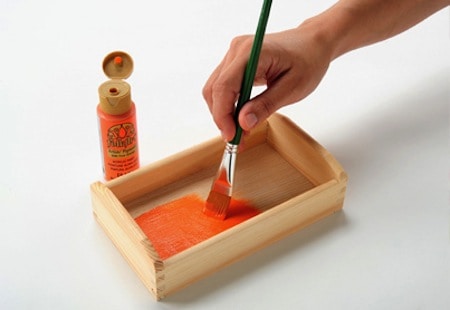 Painting a small wooden tray with FolkArt acrylic paint in orange using a paintbrush