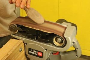 Sanding the outside of the bowl on the wooden spoon using a belt sander.