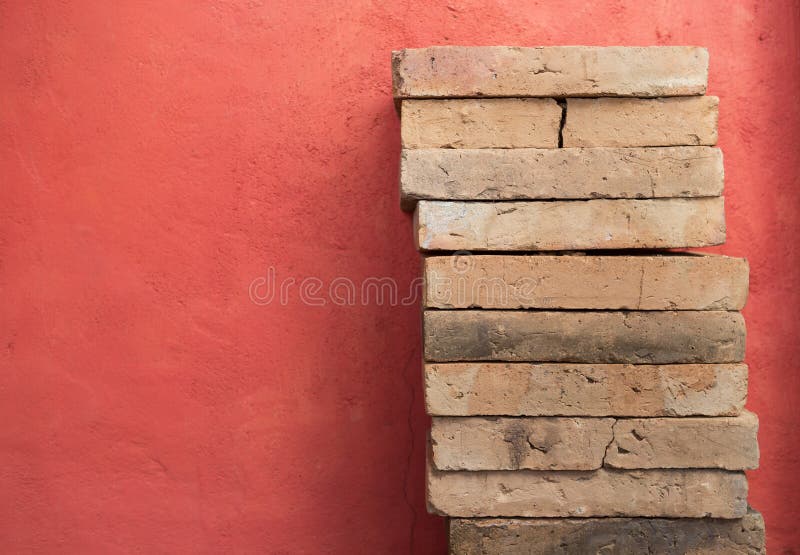 Clay brick stack over red cement wall background. Construction concept stock photos