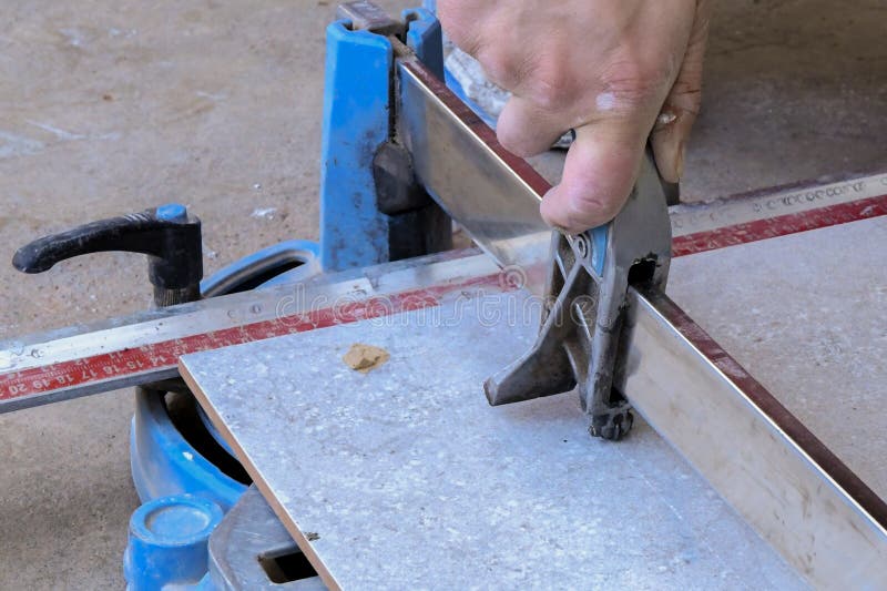 Worker placing a big ceramic tile in a cutter and cutting tile stock images