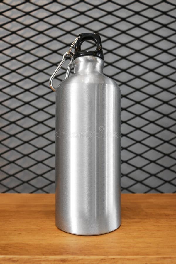 Metallic water bottle and carabiner on wood shelf background. Insulated container for your design. Metallic water bottle and carabiner on wood shelf background stock photo