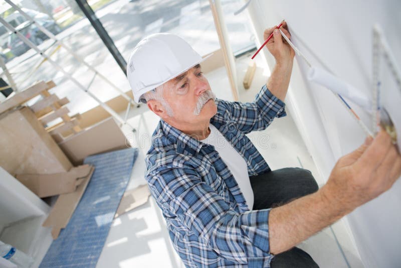 Old construction worker measuring wall stock photography