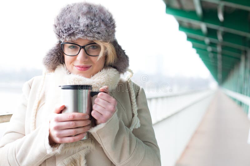 Portrait of smiling woman in warm clothing holding insulated drink container royalty free stock images