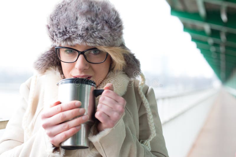 Portrait of woman drinking coffee from insulated drink container during winter royalty free stock photography