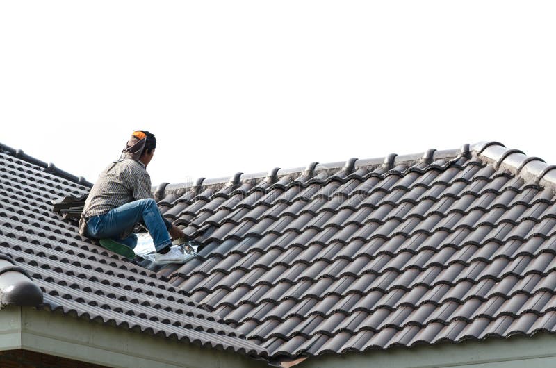 Roofing - construction worker standing on a roof covering it wit stock photo