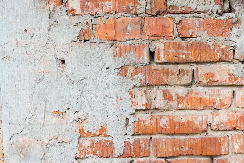 Texture of an old broken red brick wall with cement mortar. Background of red clay brick on a broken wall with cement mortar and. Plaster stock photo