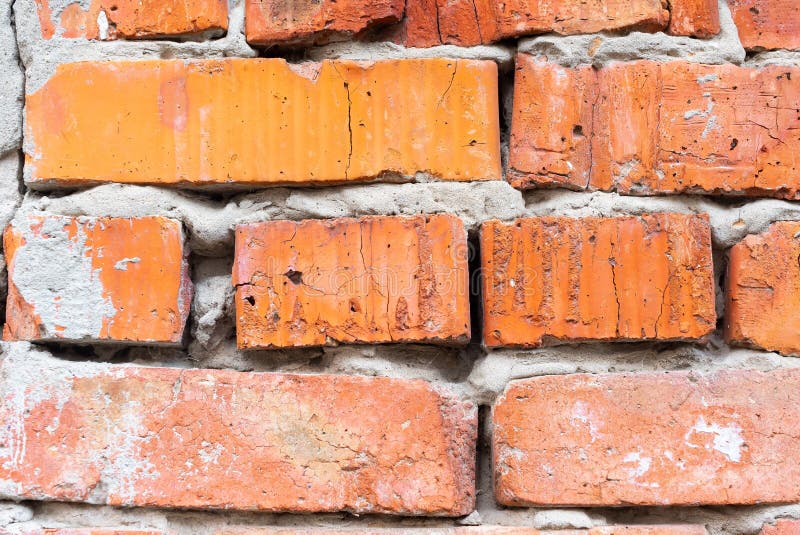Texture of an old orange brick wall with cracks. Background of adored clay brick with cracks and cement mortar with plaster.  royalty free stock photo