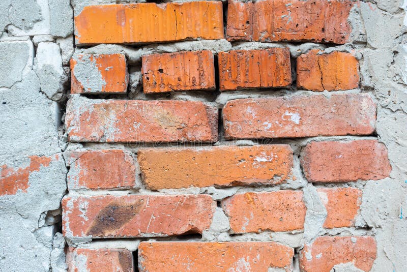 Texture of an old orange brick wall with cracks. Background of red clay brick with cracks with cement mortar and plaster.  stock image
