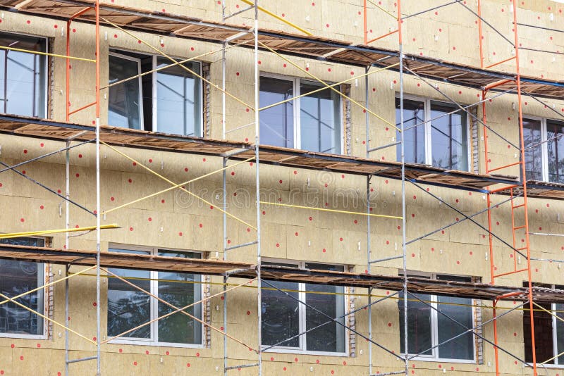 Thermal insulation of house wall with mineral wool. scaffolding near facade of a building stock image