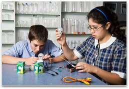 Two students with several batteries, light globe & connecting wires.